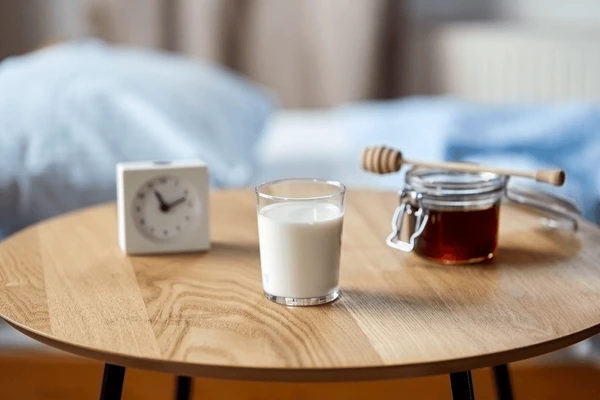 bedtime along with a table having glass of milk and tea and a clock